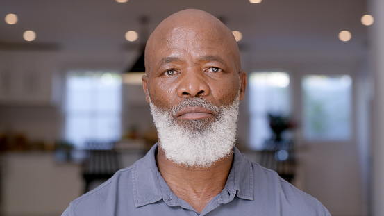 Black man, senior and face portrait at home in retirement with a grey beard with identity, freedom and serious expression. Pension, individuality and pension lifestyle of African male in a room