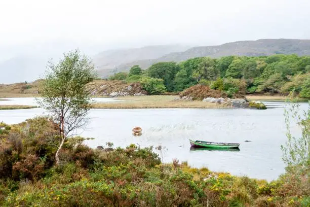 Small green boat in the tranquil water of Lough Leane lake in County Kerry in the Republic of Ireland