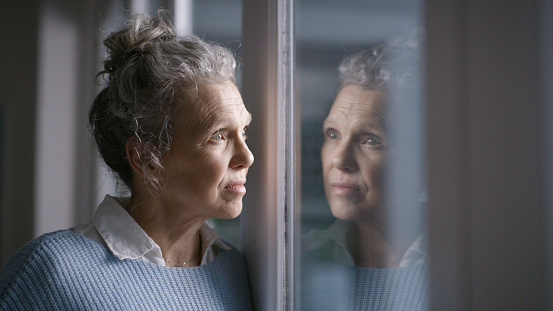 Depression, lonely and thinking senior woman in a nursing home with mental health problem, idea and sad with a window reflection. Anxiety, stress and elderly person with fear, depressed and dementia