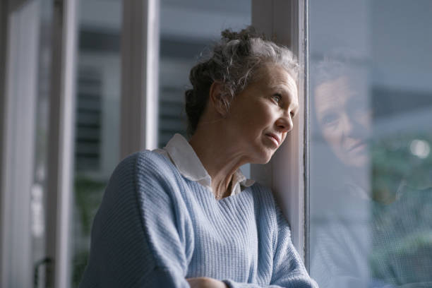 istock Sad old woman with depression at window in house thinking about future, mental health problem and life insurance policy. Senior grandma in retirement depressed with anxiety, alzheimer and dementia 1452001295
