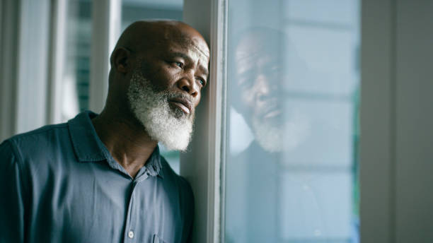istock Depression, window and sad old man with stress, mental health problems or depression in retirement at home alone. Frustrated, worry and unhappy African elderly person frustrated or worried by debt 1452001994