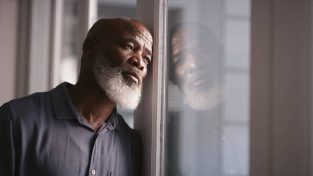 tristesse, dépression ou épuisement professionnel de l’homme noir à la fenêtre avec santé mentale, maux de tête ou anxiété à la maison. homme solitaire, stressé ou déprimé qui pense à un problème financier, à une conformité en matière de - défaite photos et images de collection