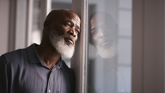Sad, depression or black man burnout at window with mental health, headache or anxiety in house. Lonely, stress or depressed man thinking for financial problem, health compliance or finance policy