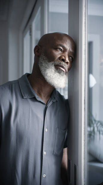 istock Retirement, depression and black man in home thinking of regret, problem and sadness at window. Sad, senior and depressed person suffering with thoughts of mental health, loneliness and grief. 1452002012