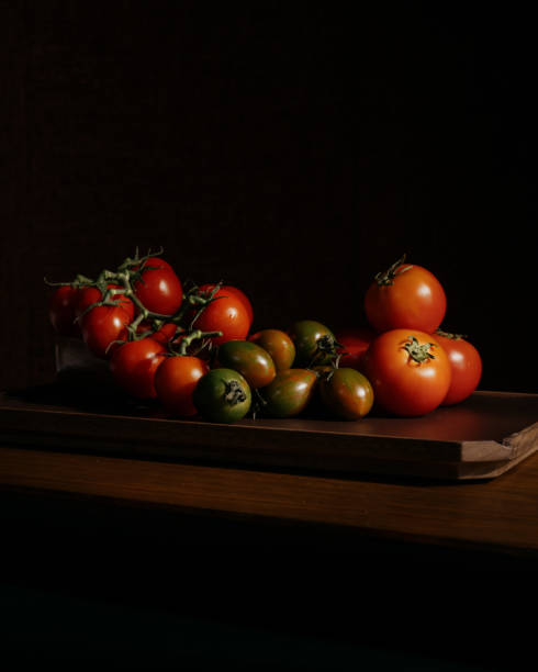 tomatoes on wood in a dark background stock photo