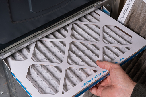 Replacing dirty furnace filter in home by man