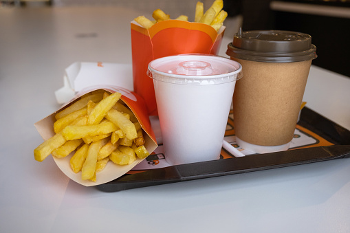Fast food on a tray in a restaurant. French fries, a glass with a milkshake, coffee