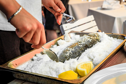 Branzino or Mediterranean sea bass whole roasted in salt fish filleted at the table by a waiter at a street restaurant in Vernazza, Cinque Terre Italy