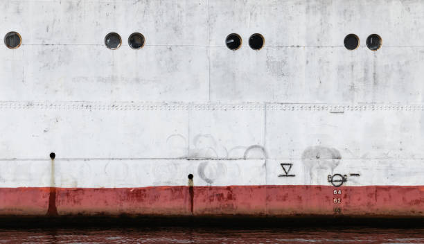 Vintage white ship hull with red waterline and portholes, industrial background texture
