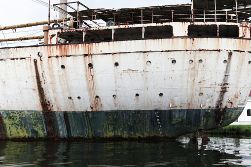 Vintage grungy white ship stern with green waterline and portholes