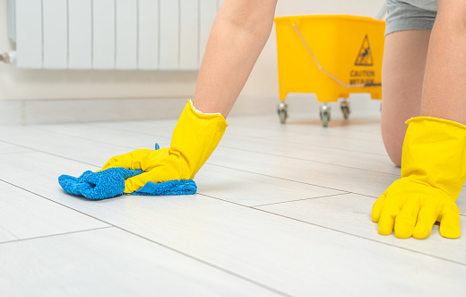 female gloves hands wipe white floor. Professional cleaner washing white wooden floor and wiping dust in living room of apartment. Cleaning service concept