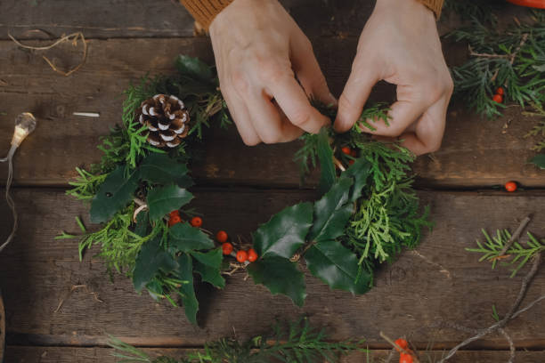istock Hands decorating Christmas wreath with holly twigs. 1452037321