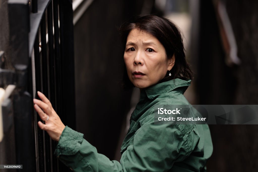 Woman looking scared in a laneway. Japanese woman with a scared expression in a narrow laneway. Women Stock Photo