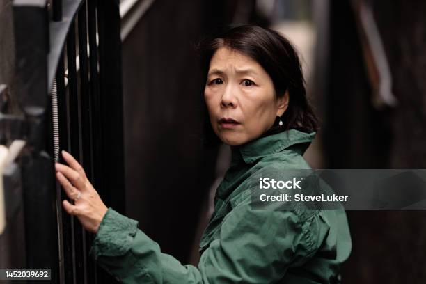 Woman Looking Scared In A Laneway Stock Photo - Download Image Now - Women, Japanese Ethnicity, Looking Over Shoulder