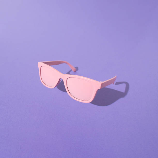 istock PInk sunglasses with sunlight shadow on purple background. Retro style. 1452039702
