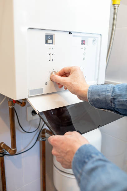 White man lowers the temperature of the gas boiler in his house due to the energy crisis stock photo