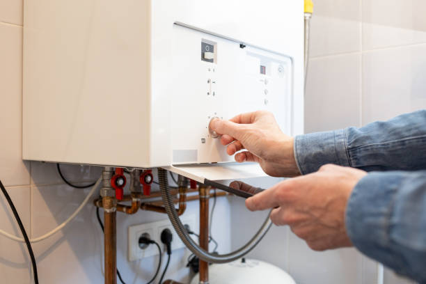 homem branco reduz a temperatura da caldeira a gás em sua casa devido à crise energética - water heater - fotografias e filmes do acervo