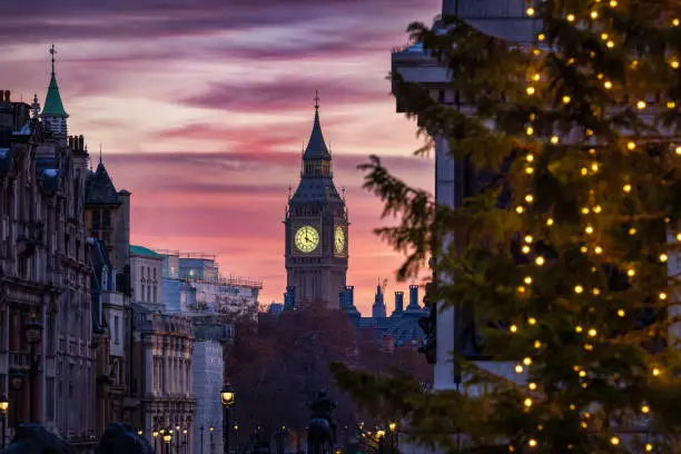 Beautiful sunset view of the Big Ben Clocktower in London, England, during winter time with the Christmas lights of the  in front