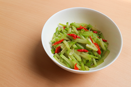 Indonesian cuisine, Tumis labu siam - Indonesian Spicy stir fry chayote, typical Indonesian daily homedish, served in white bowl over brown wooden background.
