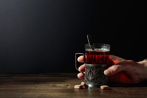 Man hand holds a traditional Russian glass holder with hot tea. Concept of the theme of despair and thinking. Copy space.