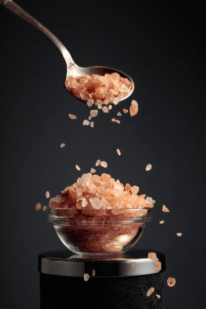 Pink salt is poured into a small bowl. stock photo
