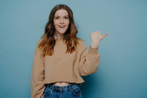 istock Excited young girl pointing finger somewhere posing over blue background 1452095668