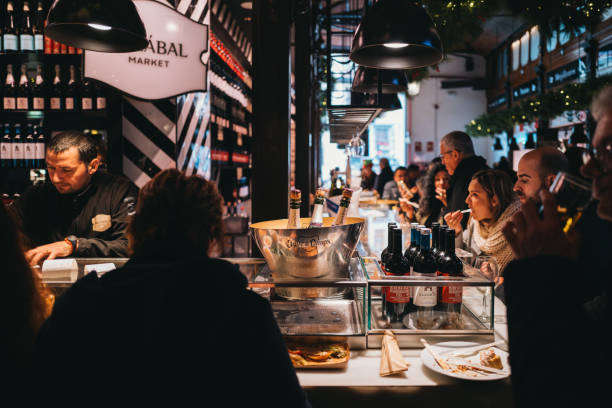 Madrid,Spain,18th December 2022 - Locals and tourists enjoying fresh food and snacks and drinks inside San Miguel food market in central Madrid, with multiple cafes and food shops available in one place. San Miguel is one of the most popular attractions for visitors to Madrid.