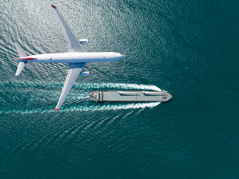 Container ship sail through airplane flying on the sea