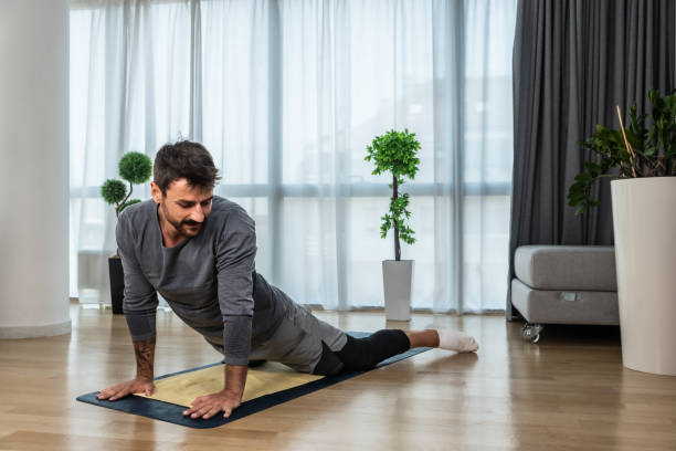 istock Young man cancer survivor practicing home workout yoga training, stretching muscles and breathing exercise for healthy life after long struggle with sickness and pain. Warmup exercises for meditation. 1452109232