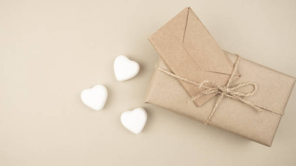 istock Gift box wrapped in kraft paper with white hearts on a light background. Holiday concept. Valentine's Day. Place for text or advertising. 1452118828