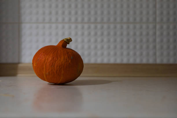 Small hokkaido pumpkin on long light wooden kitchen worktop