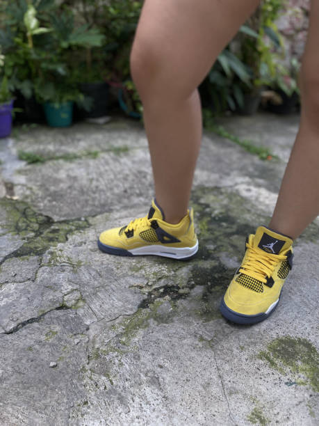 Women's feet wearing yellow Nike Air Jordan shoes Malang, East java, Indonesia - October 31,2022: Women's feet wearing yellow Nike Air Jordan shoes. nike air photos stock pictures, royalty-free photos & images