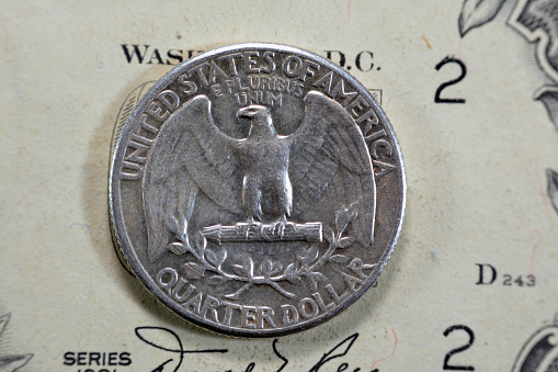The bald eagle (Haliaeetus leucocephalus) from the reverse side of a quarter dollar coin, 25 twenty five American cents series 1963, old USA vintage retro coin on USD banknote, selective focus