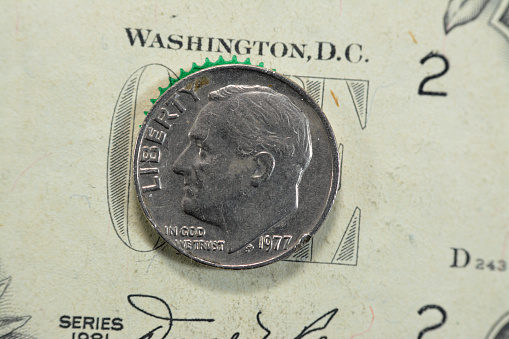 the dime coin, American money coin of 10 ten cents 1977 features the profile of Franklin D. Roosevelt the 32nd president of the United States of America, old USA vintage retro coin on USD banknote, selective focus