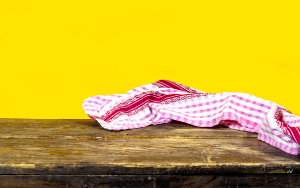 istock Empty wooden table with plaid tablecloth and wooden board over yellow background 1452130790