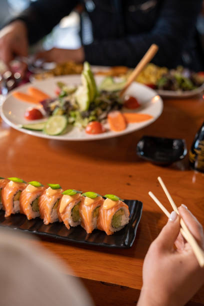 istock Women holds chopsticks to eat sushi roll 1452131230