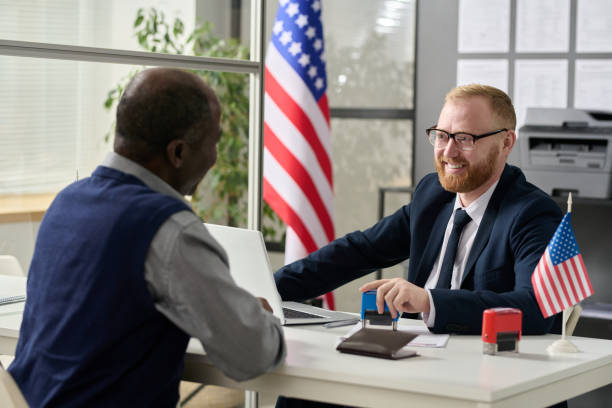 trabajador sonriente amigable que consulta a un hombre mayor en la oficina de inmigración de los estados unidos - state government fotografías e imágenes de stock