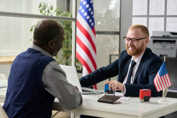 istock Friendly smiling worker consulting senior man in US immigration office 1452132472