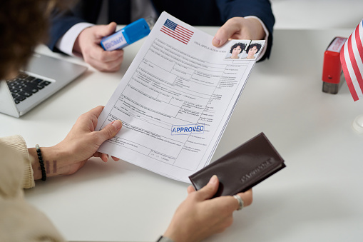 Close up of woman getting US visa in immigration office and holding approved forms