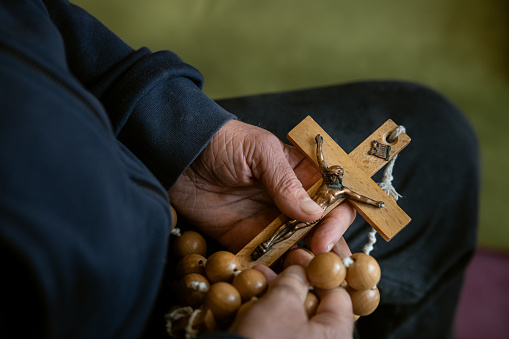 An old man prays rosaries and crosses