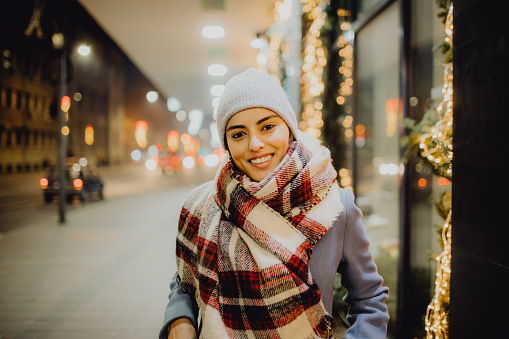 Portrait of a young Caucasian woman enjoying winter holidays in the city and looking at the camera.