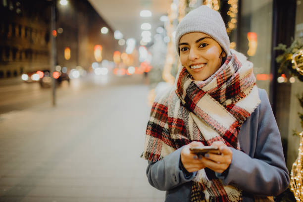 istock Smiling woman using her phone on a winter night while looking away 1452132655