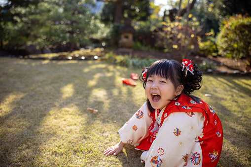 Little girl in kimono for Shichigosan playing at Japanese garden - laughing