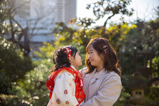 Mother and little daughter in kimono for Shichigosan looking at each other at garden