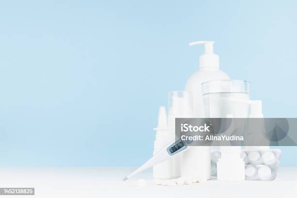Medical And Treatment Background With White Bottles Mockup For Prevent And Teraphy Disease And Sickness Health 366 Thermometer Sprays Salves Pills On White Table Blue Wall Copy Space Stock Photo - Download Image Now