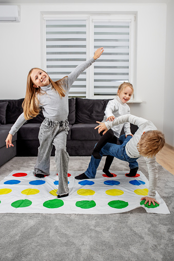 Group of children playing twister game and having fun. Concept of family, active leisure and holidays