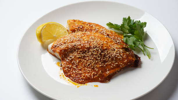istock Fresh backed red tilapia fillet on white plate with lemon and herbs 1452145911