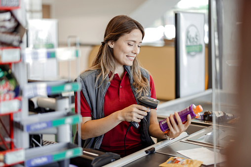 Female cashier in supermarket scanning bar code of products