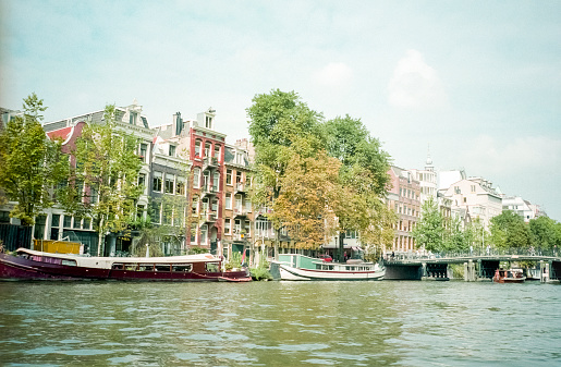 Amsterdam, Netherlands - 1984: A vintage 1980's Nikon negative film scan of the city of Amsterdam across the Amstel river canal.