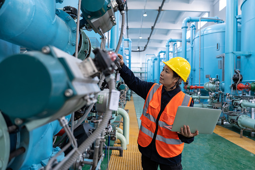 A female engineer works in a chemical plant using a laptop computer